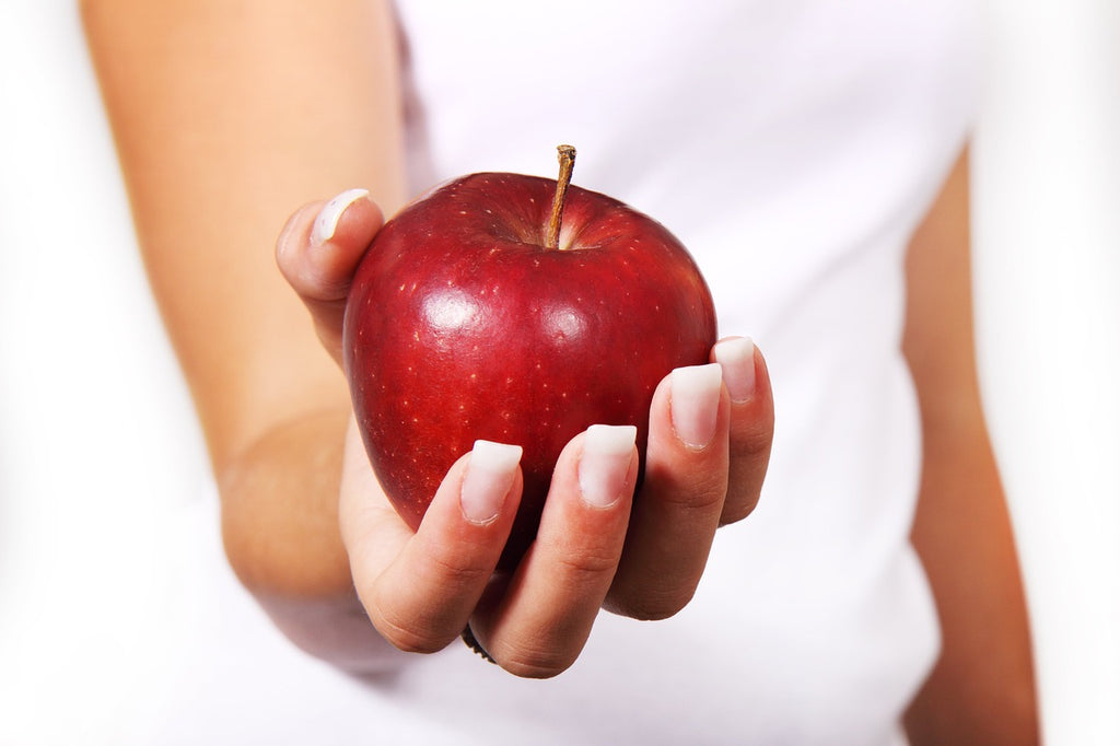 Frau hält eine roten Apfel in der Hand, Stärkung des Immunsystems und gesunde Ernährung