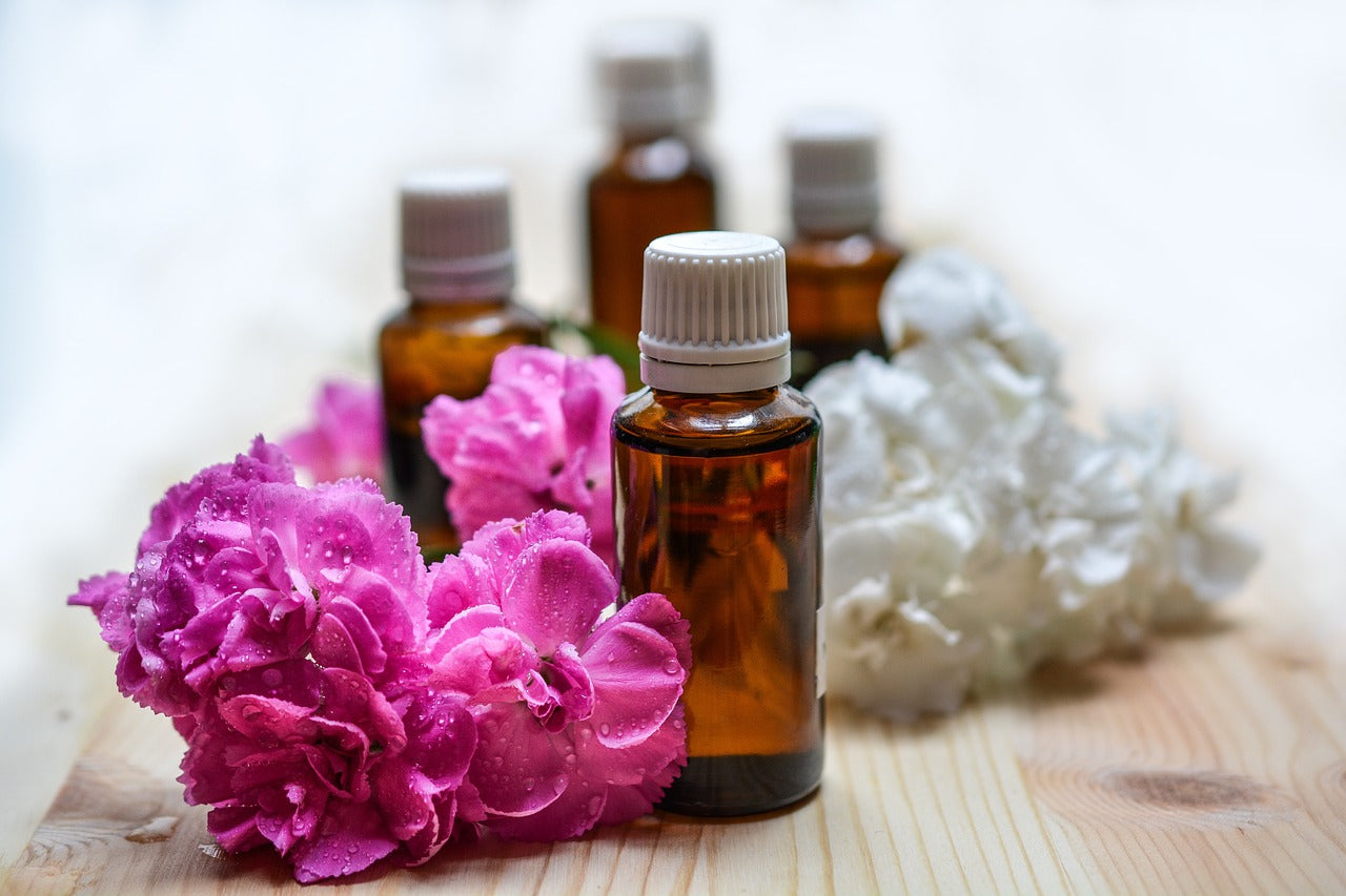 Ätherisches Öl für Aromatherapie in brauner Flasche mit Blumen aussenrum