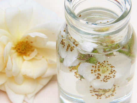 Rosenextrakt im Glas mit Blüten
