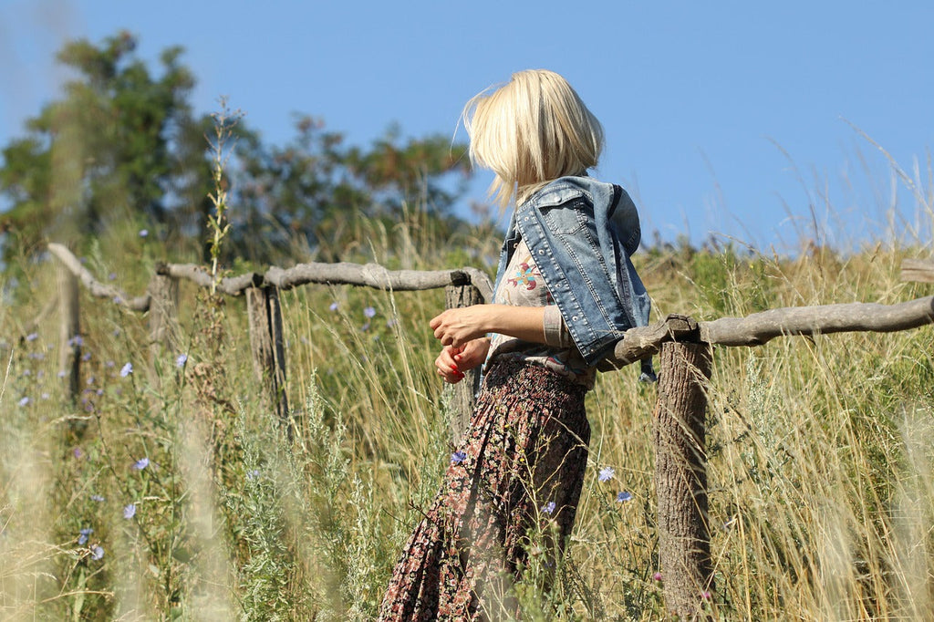 Junge blonde Frau auf einer Wiese mit Zaun