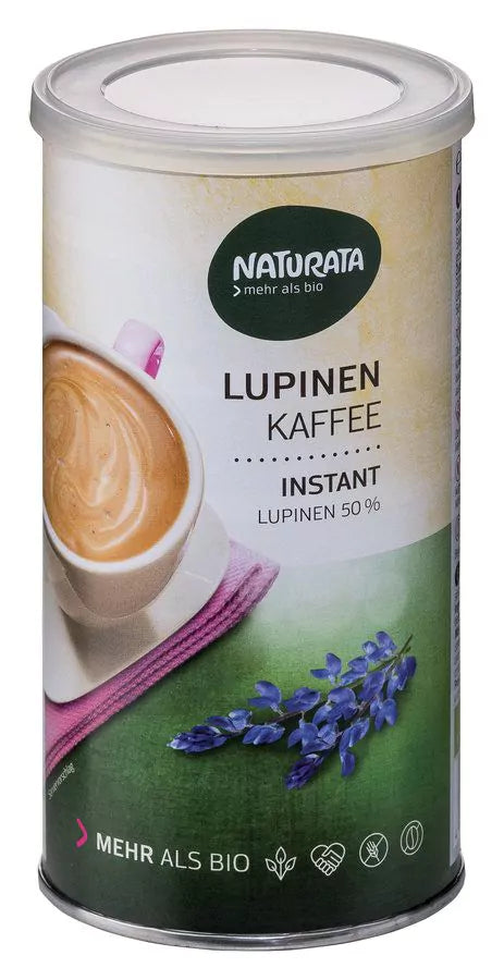 Eine zylindrische Dose Naturata Lupinen Kaffee Instant ist vor einem neutralen, hellen Hintergrund abgebildet. Die Dose hat ein Etikett, das oben das grüne Naturata-Logo zeigt und den Text 'LUPINEN KAFFEE INSTANT LUPINEN 50%'. Ein Teil einer Kaffeetasse mit cremigem Kaffee Latte und ein pinkes Tuch sind auf dem Etikett zu sehen, zusammen mit blauen Lupinenblüten auf einem grünen Feld im unteren Bereich. Unten auf der Dose steht 'MEHR ALS BIO' und verschiedene Symbole.