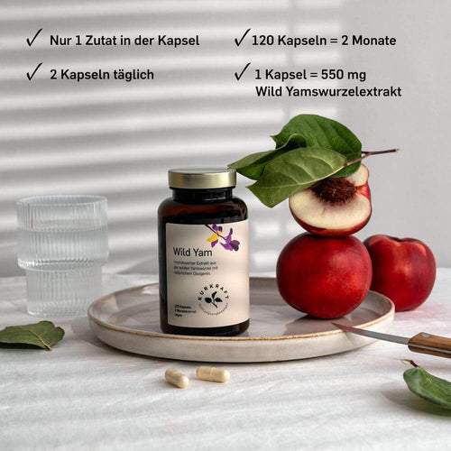 Auf einem teinteller steht eine Dose der Wild Yam Kapseln . Vor dem Teller 2 Kaseln daneben ein Glas Wasser und 2 Nektarinen, sowie eine halbe mit Kern