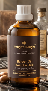 Ein Produktbild des „Relight Delight Man Barber Oil Beard & Hair“ in einer 100ml-Braunglasflasche mit weißem Schraubverschluss. Die Flasche steht im Rampenlicht auf einer rustikalen Holzscheibe, flankiert von Argan-Nüssen und einer Vanilleschote. Im warm ausgeleuchteten, leicht unscharfen Hintergrund eines Barbershops sind ein klassischer Frisierkamm, ein Rasiermesser sowie eine Ledertasche und weitere Pflegeflaschen zu erkennen. Die goldene Schrift auf dem dunkelbraunen Etikett ist deutlich lesbar.
