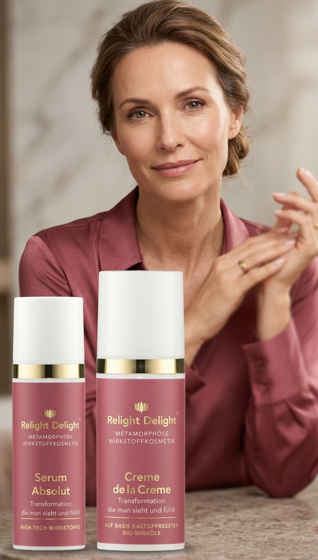 „Eine elegante, reifere Frau mit strahlender Haut und hochgestecktem Haar sitzt lächelnd im Hintergrund. Sie trägt eine altrosa Seidenbluse, die farblich perfekt auf die zwei im Vordergrund platzierten Kosmetikprodukte abgestimmt ist. Vor ihr stehen eine Flasche 'Serum Absolut' und ein Tiegel 'Creme de la Creme' der Marke Relight Delight auf einer edlen Marmoroberfläche.“