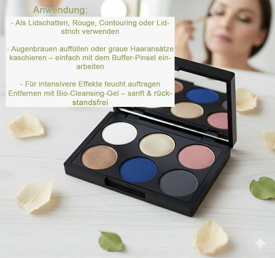 Eine offene schwarze Lidschattenpalette mit sechs Farben auf einem hellen Holztisch, umgeben von Blütenblättern. Im Hintergrund schminkt sich unscharf eine Frau. Daneben eine Textbox mit "Anwendung:" und Aufzählungspunkten zu den vielfältigen Verwendungsmöglichkeiten der Palette als Lidschatten, Rouge, Contouring, Lidstrich, zum Auffüllen der Augenbrauen und Kaschieren grauer Haaransätze, sowie Hinweise zur feuchten Anwendung und Entfernung mit Bio-Cleansing-Gel. Von der Marke Thats me Organic