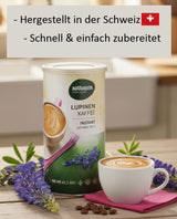 Eine Dose Naturata Lupinen Kaffee Instant steht auf einem rustikalen Holztisch. Links und rechts von der Dose sind frische, lilafarbene Lupinenblüten arrangiert. Vor der Dose steht eine weiße Tasse mit einem liebevoll zubereiteten Kaffee Latte, der auf einem pinken Tuch platziert ist. Vereinzelt liegen Kaffeebohnen auf dem Tisch. Im unscharfen Hintergrund ist eine helle Küchenumgebung mit einem Fenster und einer Spüle zu erkennen.