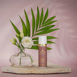 Tube in Altrosa mit goldener Aufschrift Metamorphose Wirkstoffkosmetik, Serum Absolut- frei von Parfüm 30ml -  Relight Delight steht qauf einem hellen flachen Stein. Links eine kleine Vase mit  weißen Rosen und ein Palmblatt. Der Hintergrund ist rosa gehalten