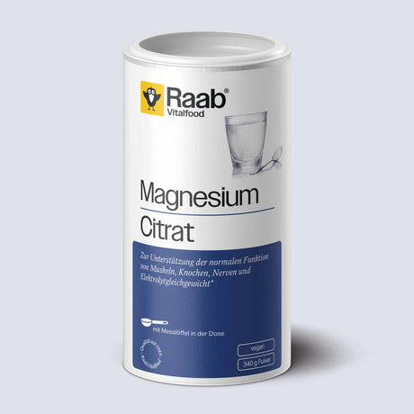 Weiße Dose mit weiß-blauem Etikett von Raab Vitalfood Magnesiumcitrat Pulver, daneben ein Glas Wasser mit Teelöffel – Nahrungsergänzungsmittel, vegan, gut löslich