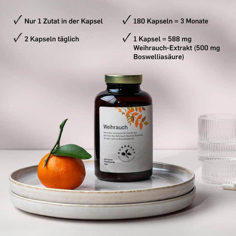 Eine Dose Weihrauchkapseln auf einem flachen Teller. Daneben eine Mandarine und rechts davon ein Glas mit Wasser