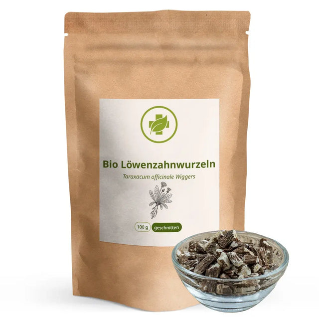 Stehende braune Papiertüte der Bio Löwenzahnwurzeln von vitalundfitmit100 mit einer gefüllten Glasschale mit getrockneten, geschnittenen Löwenzahnwurzeln davor
