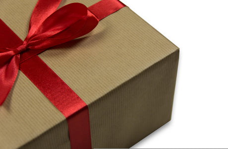 Geschenk Päckchen in goldenem Papier mit roter Schleife