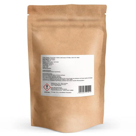 Rückseite der Niacin-Verpackung von vitalundfitmit100 mit weißem Etikett für Spezifikationen, Inhaltsstoffe und gesetzliche Gefahrenhinweise inklusive GHS-Achtungssymbol und Herstelleradresse in Jüchen.