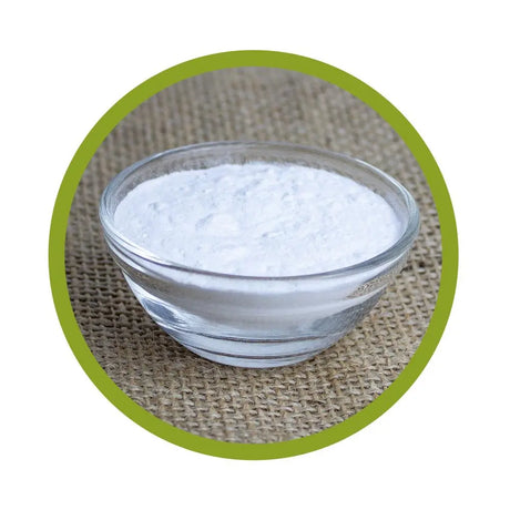 Kleine Schale aus Glas, gefüllt mit feinem, weißem Nicotinsäure-Pulver (Niacin), platziert auf einem Jute-Untergrund mit grünem Kreis-Rahmen.