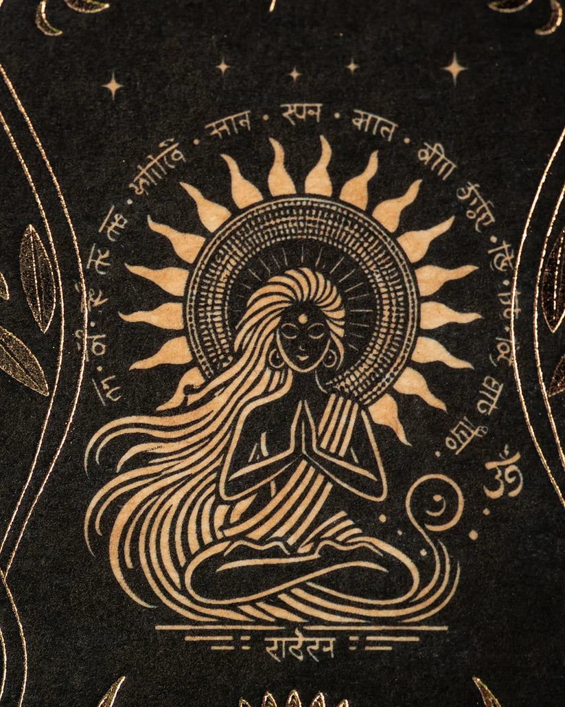 Detailaufnahme der Verpackung mit einer im Schneidersitz meditierenden Frauenfigur vor einem strahlenden Sonnenrad mit Sanskrit-Schriftzeichen und goldenen Verzierungen.