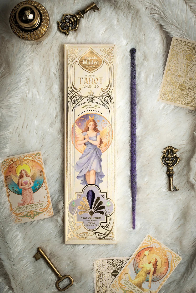 Flachliegendes Arrangement des Sagrada Madre Tarot Angels Räucherwerks auf weißem Fell mit Verpackung, lila Stäbchen, zwei Engelkarten und antik aussehenden Messingschlüsseln.