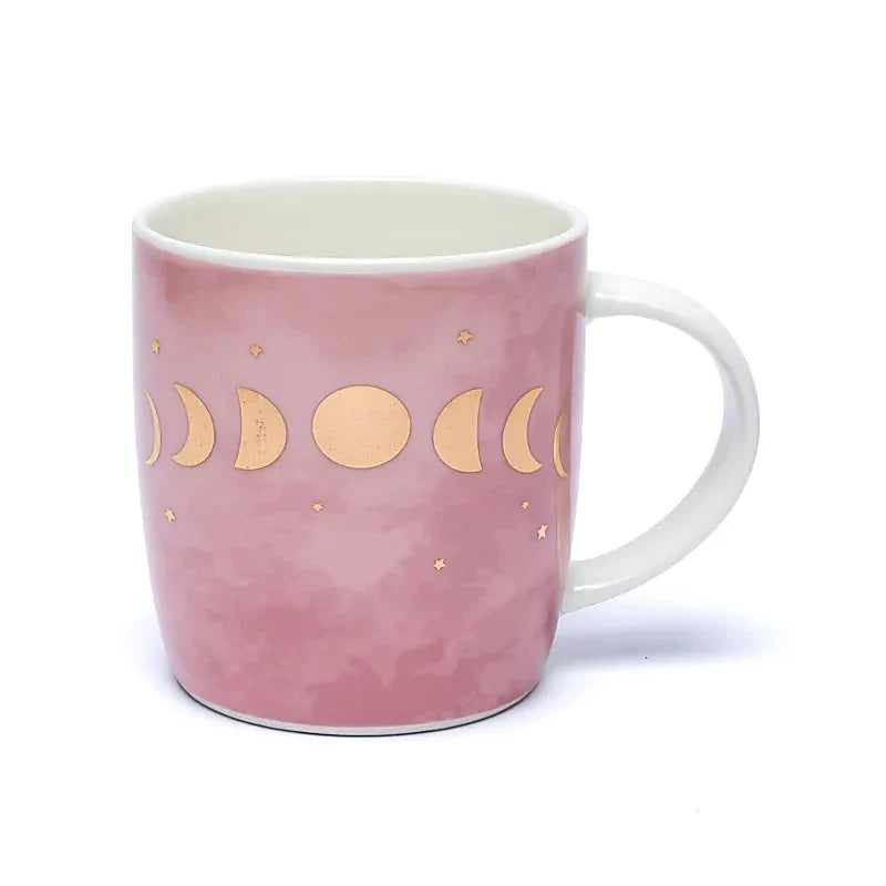 Rosa Teetasse, verziert mit goldenen Mondphasen. Die Tasse hat einen weißen Henkel.